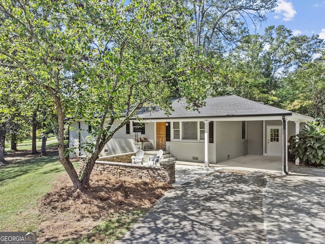 ranch-style house featuring driveway, a shingled roof, an attached carport, crawl space, and brick siding