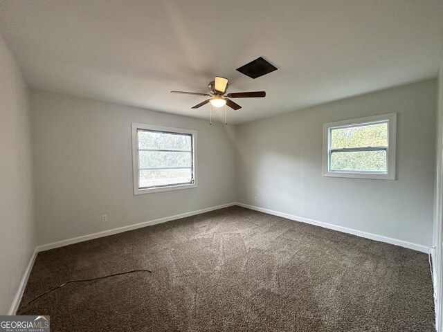 spare room with baseboards, dark colored carpet, and ceiling fan