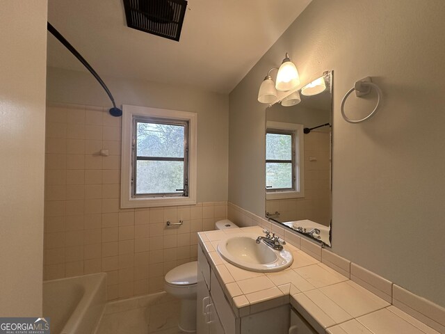 bathroom featuring vanity, visible vents, tile walls, toilet, and shower / bathtub combination