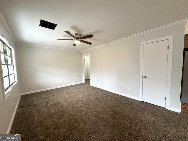 spare room with baseboards, dark carpet, and crown molding