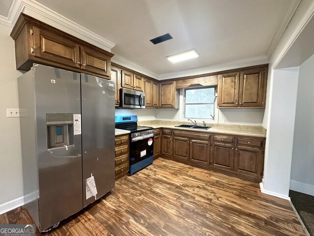 kitchen featuring a sink, stainless steel appliances, crown molding, light countertops, and dark wood-style flooring