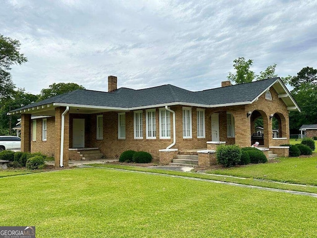 ranch-style home featuring brick siding, a chimney, and a front lawn