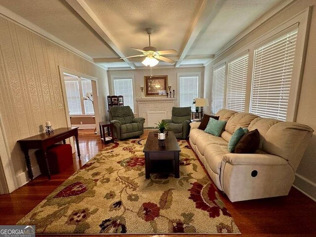 living room featuring beam ceiling, ceiling fan, ornamental molding, and hardwood / wood-style flooring