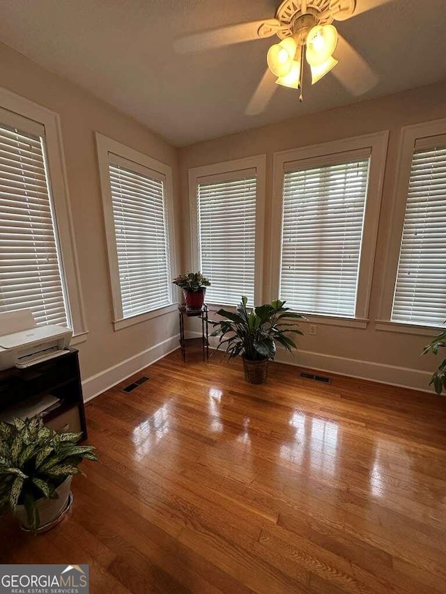 interior space featuring a ceiling fan, baseboards, visible vents, and wood finished floors