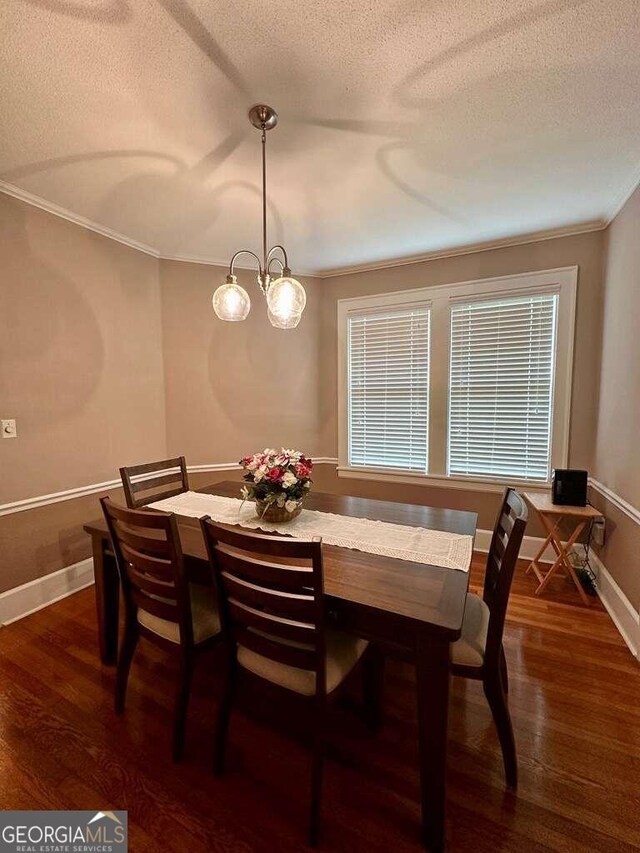 dining space with crown molding, dark wood-type flooring, a textured ceiling, and an inviting chandelier