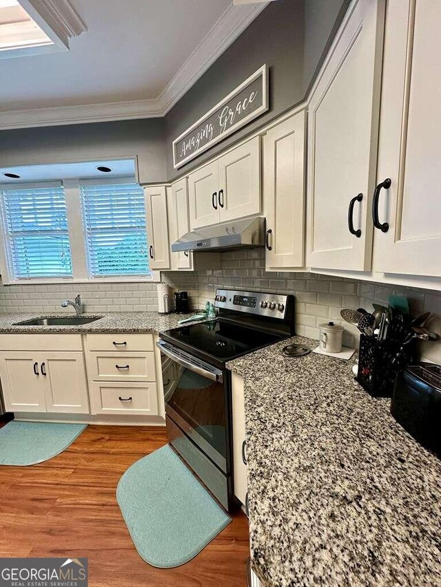 kitchen featuring hardwood / wood-style flooring, decorative backsplash, wall chimney exhaust hood, and stainless steel electric range