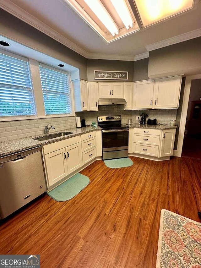 kitchen with appliances with stainless steel finishes, wood-type flooring, and white cabinets