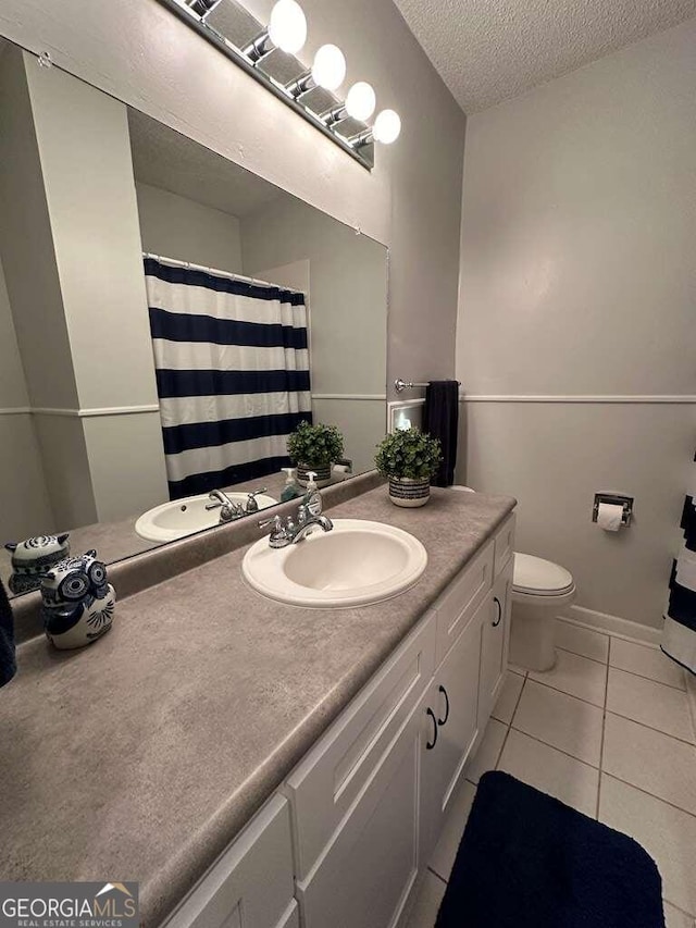 full bathroom with toilet, a textured ceiling, vanity, baseboards, and tile patterned floors