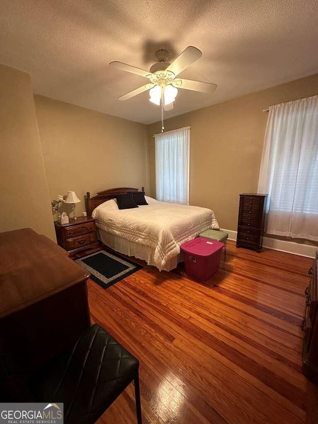 bedroom with ceiling fan, a textured ceiling, and wood-type flooring