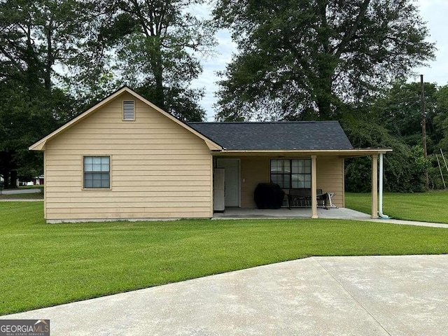 rear view of house featuring a yard and a shingled roof