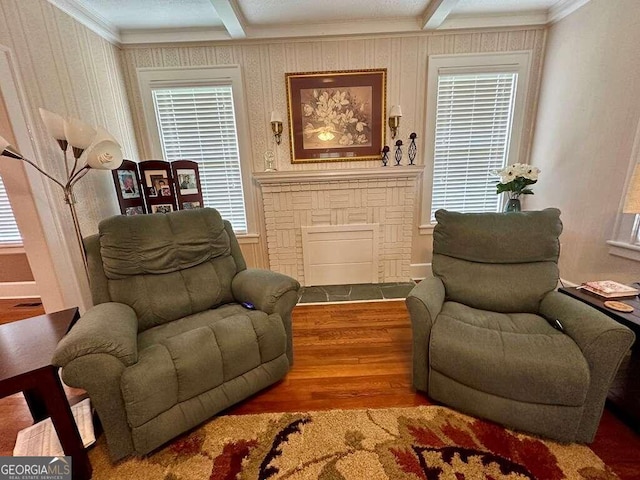 sitting room featuring a brick fireplace, ornamental molding, beamed ceiling, and wood finished floors