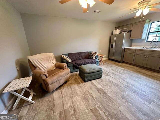 living room with ceiling fan, sink, and light hardwood / wood-style floors