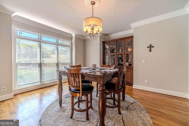 dining area featuring light hardwood / wood-style floors, ornamental molding, and a chandelier