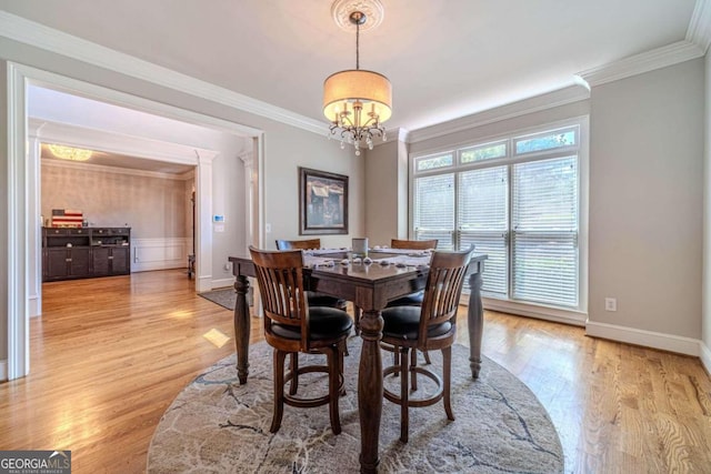 dining space with crown molding, light hardwood / wood-style flooring, and a chandelier