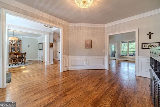 unfurnished living room featuring hardwood / wood-style flooring, ornamental molding, and a chandelier