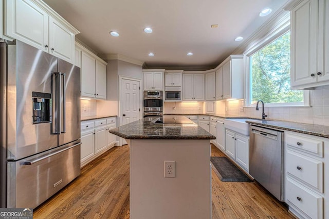 kitchen with light wood-type flooring, white cabinetry, appliances with stainless steel finishes, and a kitchen island