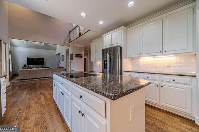 kitchen with black electric stovetop, light hardwood / wood-style flooring, a kitchen island, stainless steel refrigerator with ice dispenser, and white cabinetry