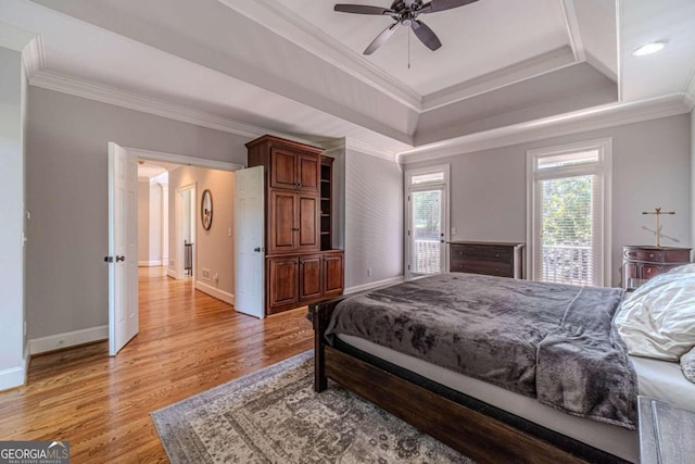 bedroom with light hardwood / wood-style floors, a raised ceiling, crown molding, and ceiling fan