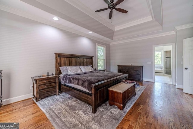 bedroom with ceiling fan, a raised ceiling, crown molding, and hardwood / wood-style floors