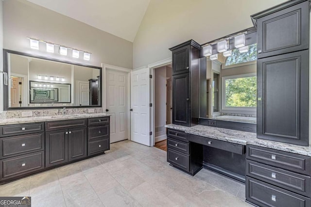 bathroom with high vaulted ceiling, a tub, tile patterned flooring, and vanity