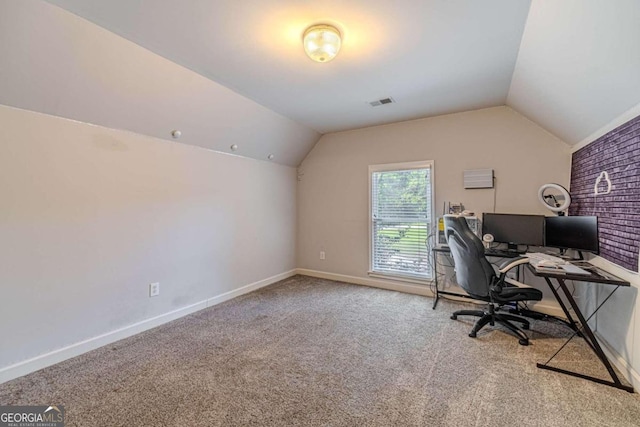 carpeted office space with vaulted ceiling and brick wall