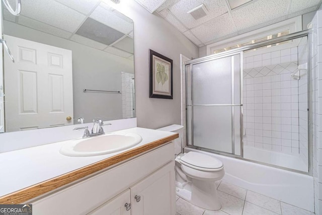 full bathroom with a paneled ceiling, toilet, vanity, tile patterned floors, and shower / bath combination with glass door