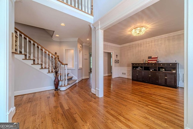 foyer entrance featuring crown molding, decorative columns, and wood-type flooring