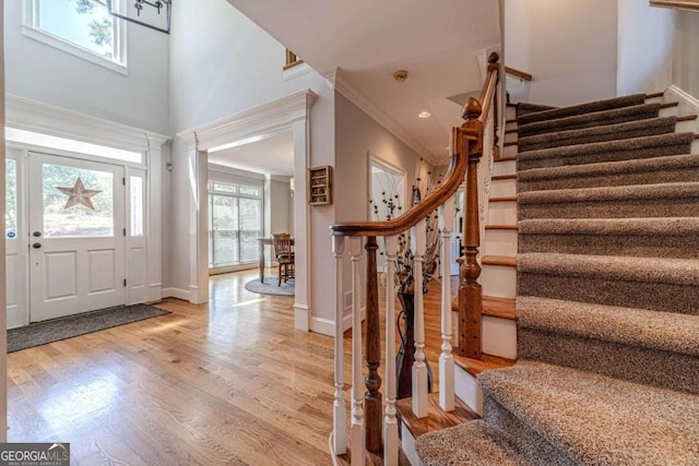 foyer featuring a towering ceiling, light hardwood / wood-style floors, and ornamental molding