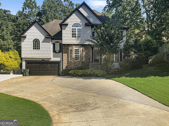 view of front of home with an attached garage, fence, concrete driveway, stone siding, and a front yard