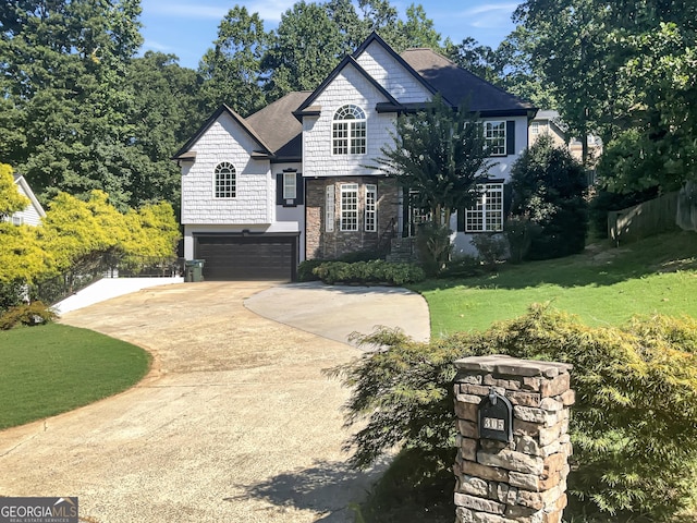 view of front facade featuring an attached garage, stone siding, concrete driveway, and a front yard