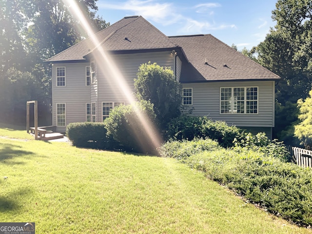 view of side of home featuring a shingled roof and a lawn