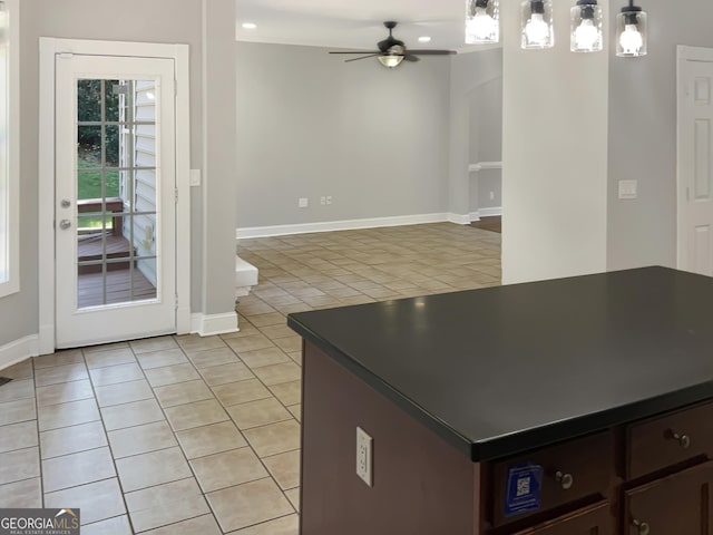 kitchen featuring light tile patterned floors, a ceiling fan, dark countertops, dark brown cabinets, and pendant lighting