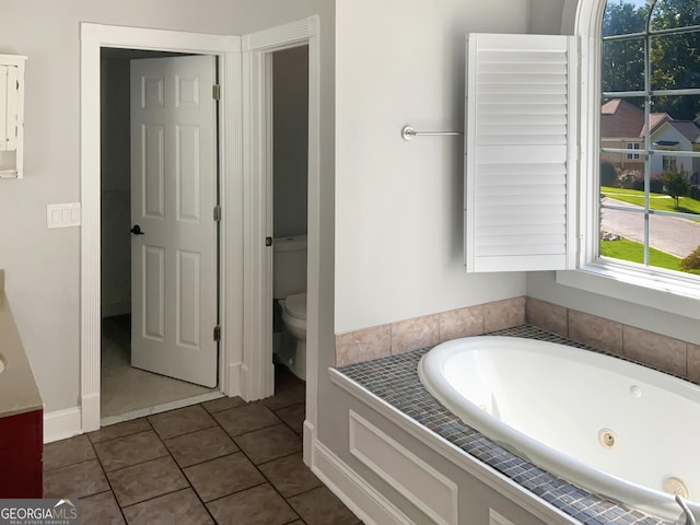 full bathroom with a jetted tub, tile patterned flooring, and toilet