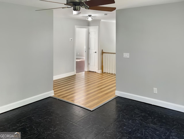 unfurnished room featuring a ceiling fan and baseboards