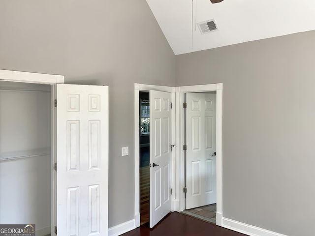 unfurnished bedroom featuring baseboards, visible vents, vaulted ceiling, and dark wood-type flooring