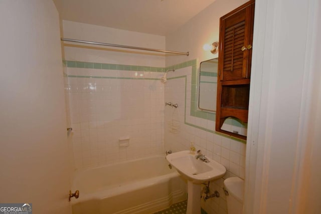 bathroom featuring tile walls, toilet, and tiled shower / bath combo