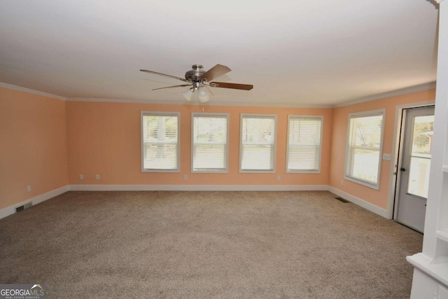 carpeted empty room featuring ceiling fan, a healthy amount of sunlight, and ornamental molding