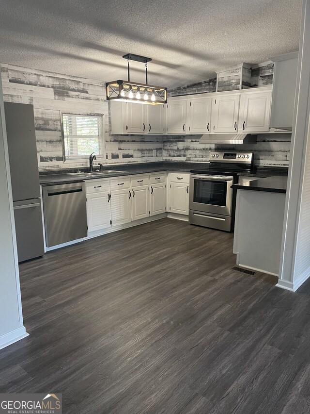 kitchen with stainless steel appliances, pendant lighting, dark wood-type flooring, and a textured ceiling