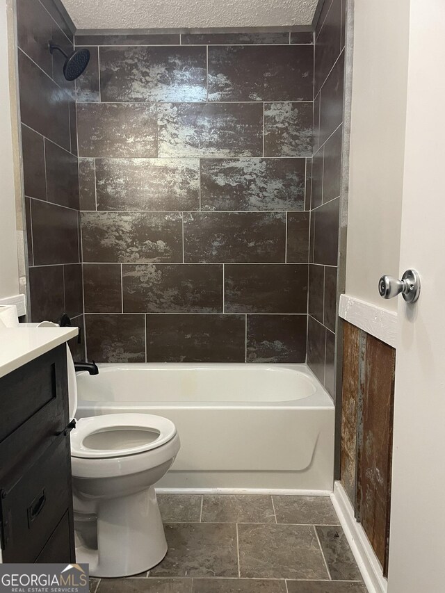 full bathroom with a textured ceiling, toilet, and tiled shower / bath