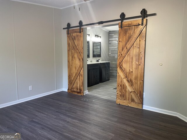 empty room featuring dark wood-type flooring, crown molding, and a barn door