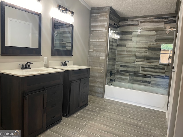 bathroom with combined bath / shower with glass door, a textured ceiling, and vanity