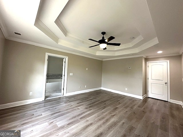 unfurnished bedroom with hardwood / wood-style floors, ornamental molding, a raised ceiling, ceiling fan, and connected bathroom