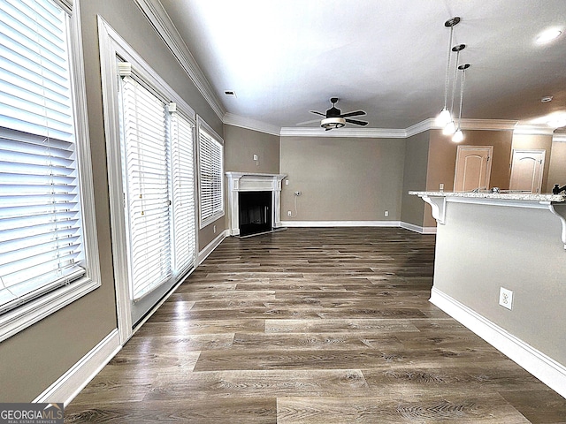 unfurnished living room featuring ceiling fan, ornamental molding, dark hardwood / wood-style flooring, and a healthy amount of sunlight