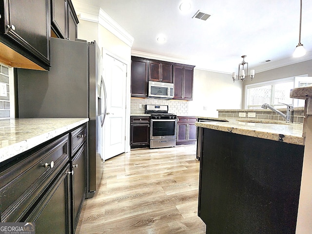 kitchen with light hardwood / wood-style flooring, tasteful backsplash, hanging light fixtures, appliances with stainless steel finishes, and sink