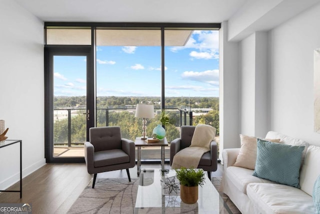 living area featuring baseboards, wood finished floors, and floor to ceiling windows