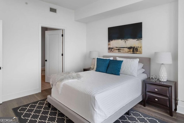 bedroom with dark wood-style floors, visible vents, and baseboards