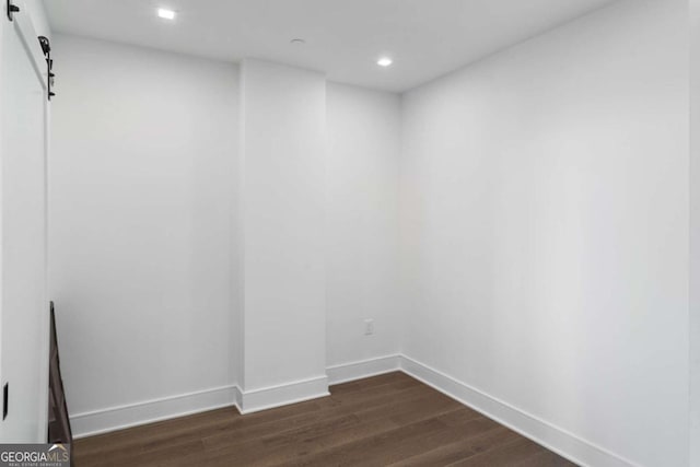 empty room featuring dark wood-type flooring and a barn door