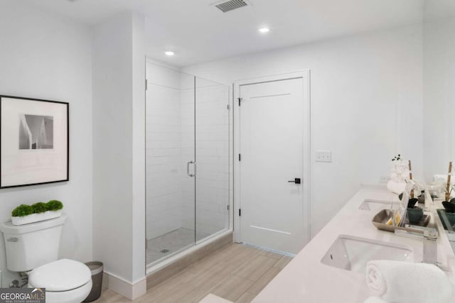 bathroom featuring double vanity, visible vents, toilet, a sink, and a shower stall