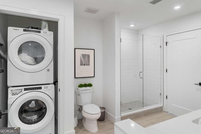 laundry area featuring light hardwood / wood-style floors and stacked washing maching and dryer