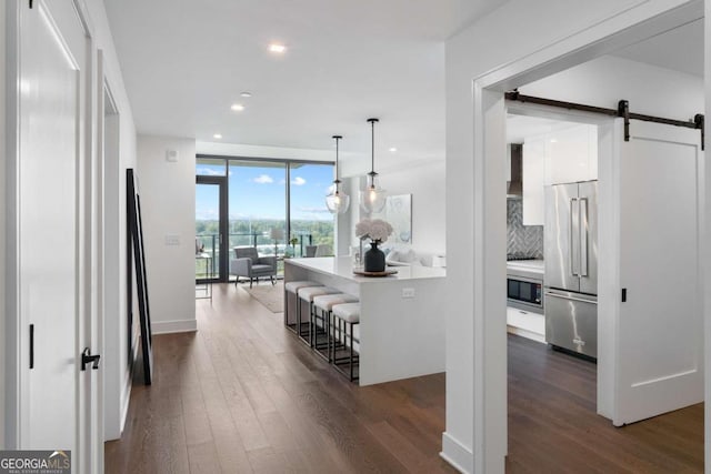 corridor featuring floor to ceiling windows, dark hardwood / wood-style floors, and a barn door